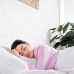 Mulher dormindo com planta ao lado da cama // Créditos: depositphotos.com / EdZbarzhyvetsky